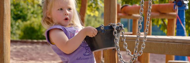 Ein Mädchen spielt mit einem Sandeimer auf dem Spielplatz.