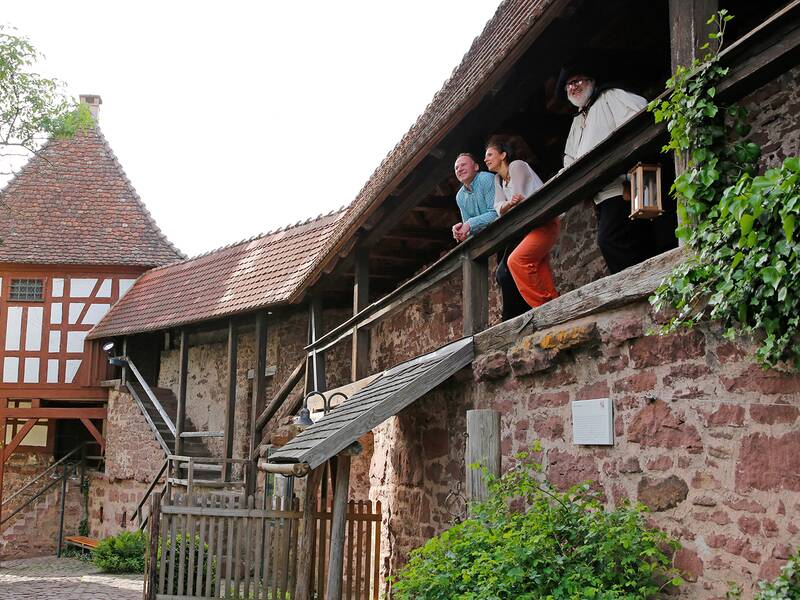 Besucher mit dem Nachtwächter auf dem Wehrgang im Schlosshof
