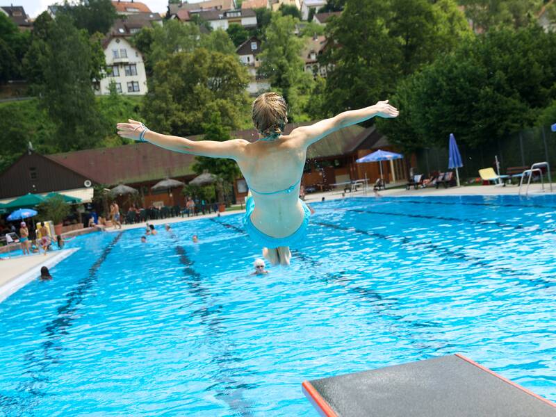 Eine Frau springt mit einem Salto ins Schwimmbecken.