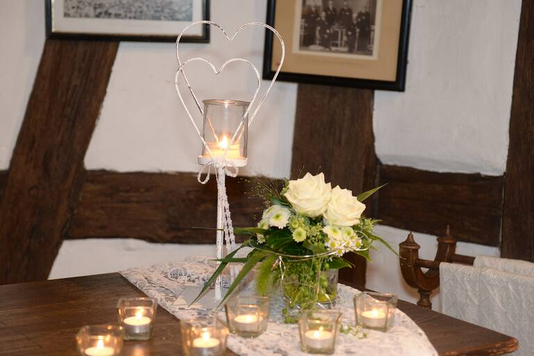 Kerzen, Blumen und Herzdeko stehen für eine Hochzeit gerichtet auf dem Tisch.