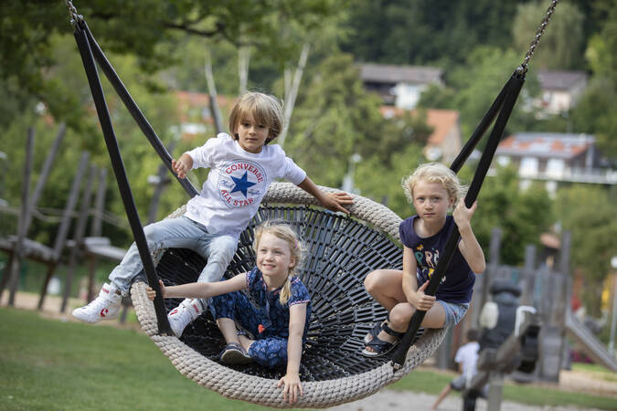 Schaukelnde Kinder auf dem Flößerspielplatz imStadtgarten