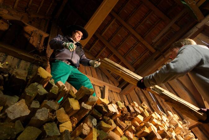 Zwei Fackler schichten Holz im Schuppen.