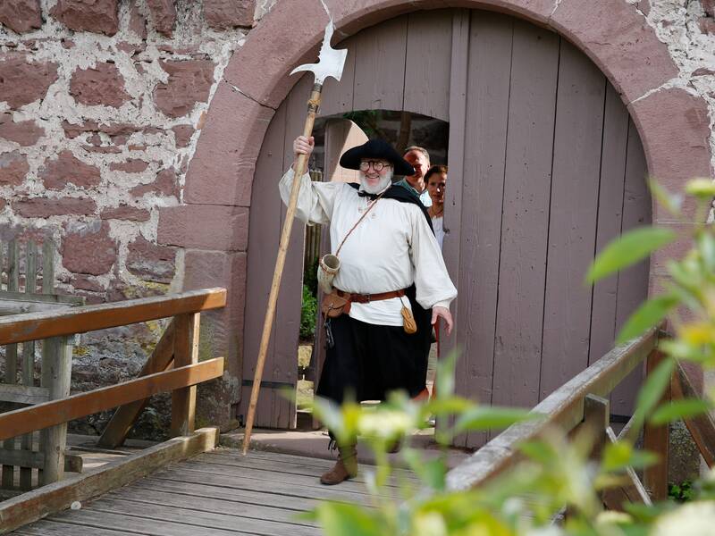 Der Nachtwächter läuft aus dem Schlosshof über eine kleine Holzbrücke.